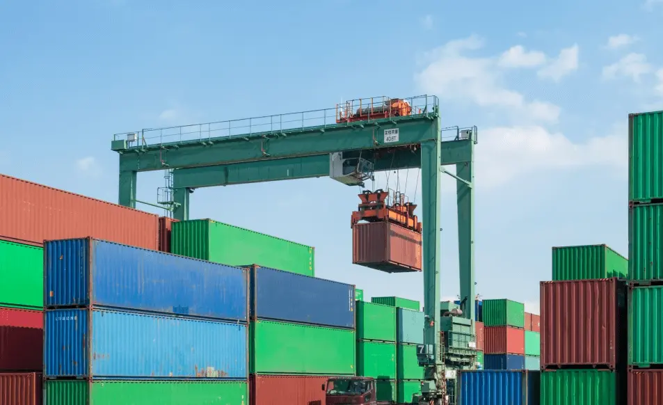 Shipping containers being handled by a crane at a port terminal