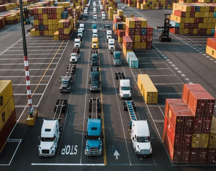 Container trucks moving through a busy port yard